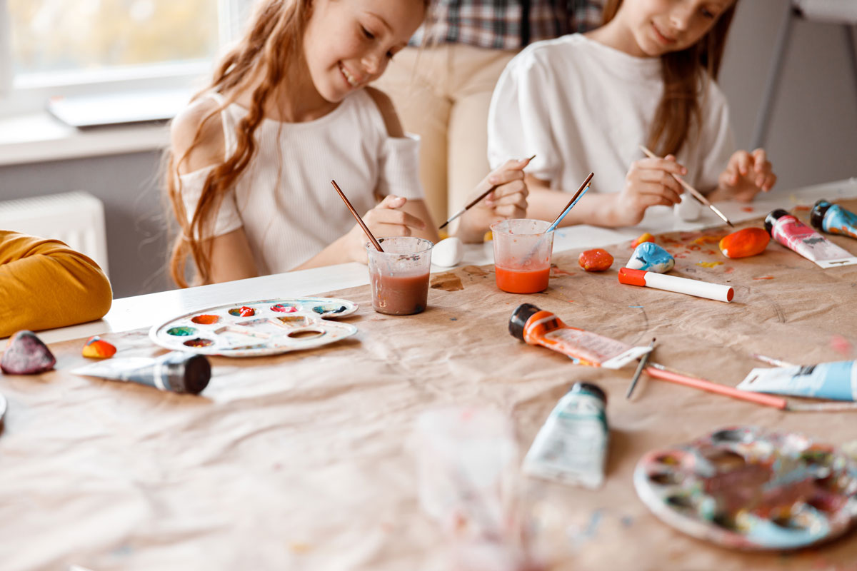 niñas haciendo manualidades pintando piedras de muchos colores